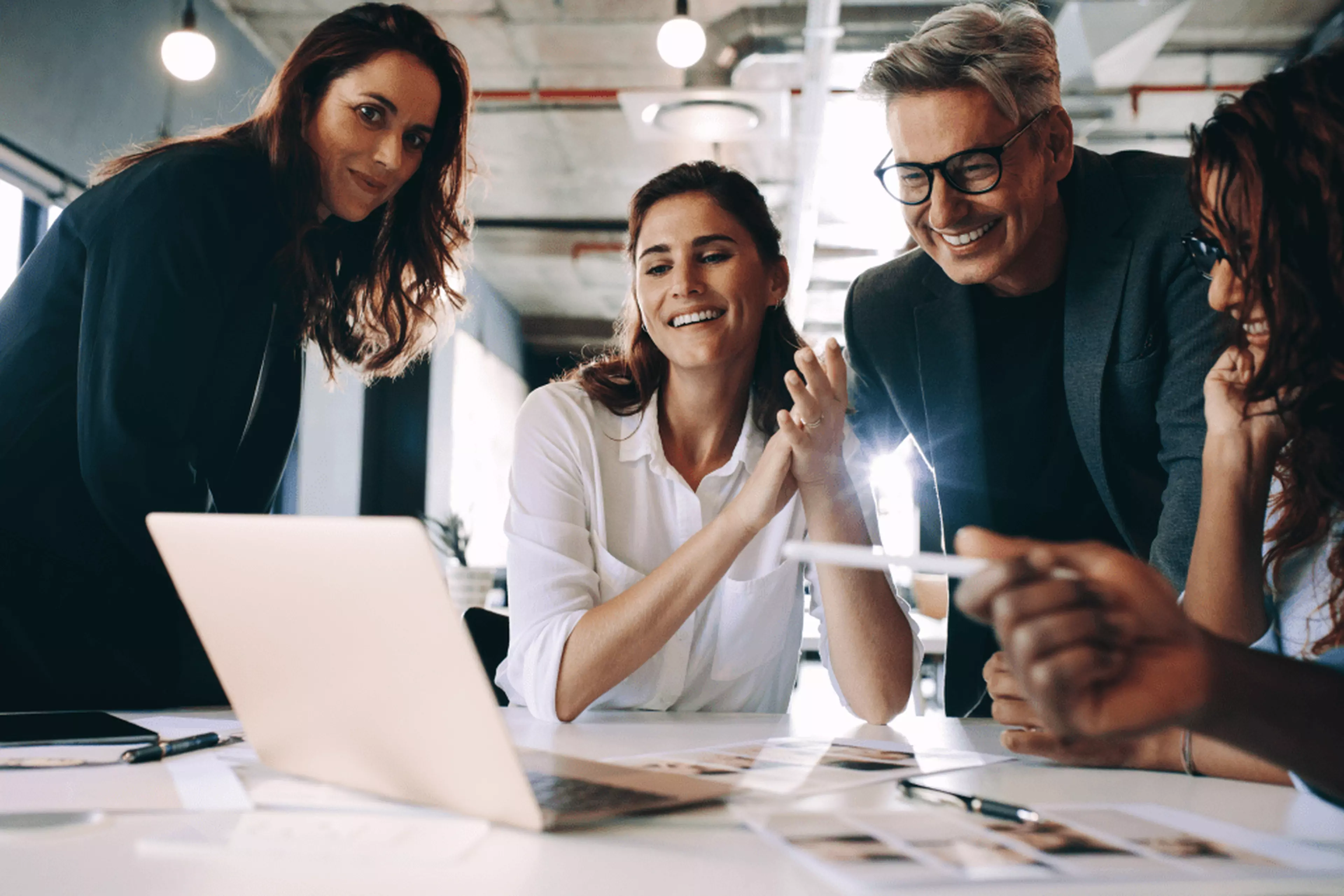 Group of happy coworkers in the office, looking at a laptop screen.