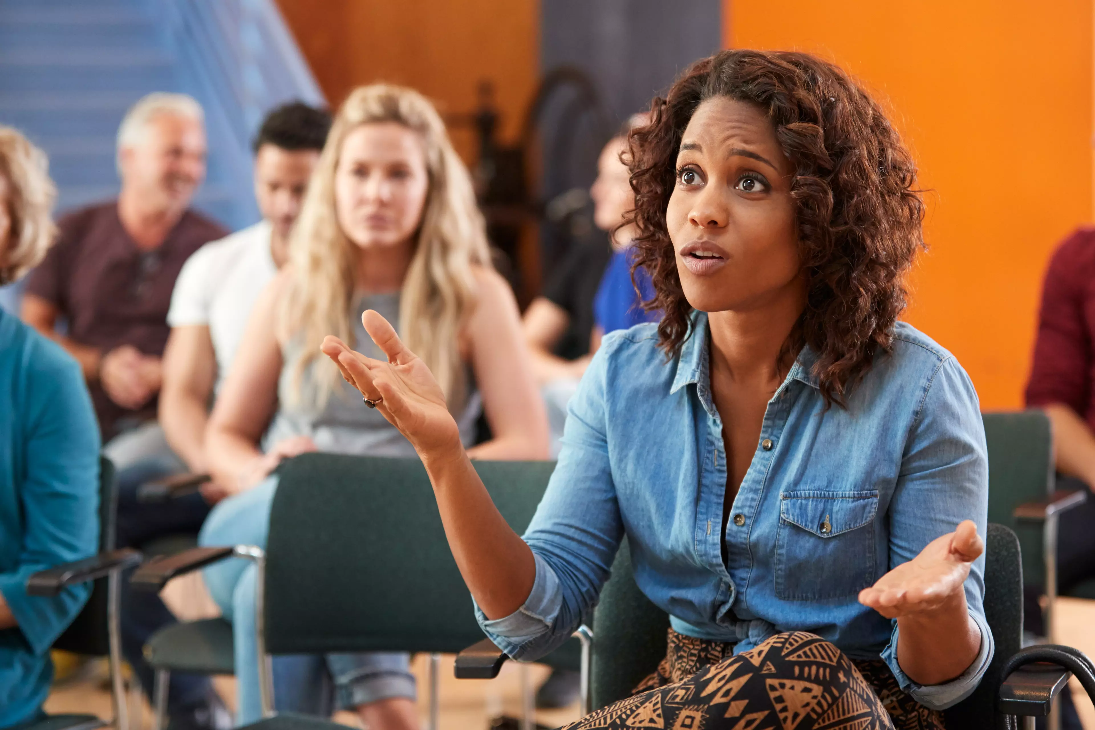 A young woman asking a question during a meeting.