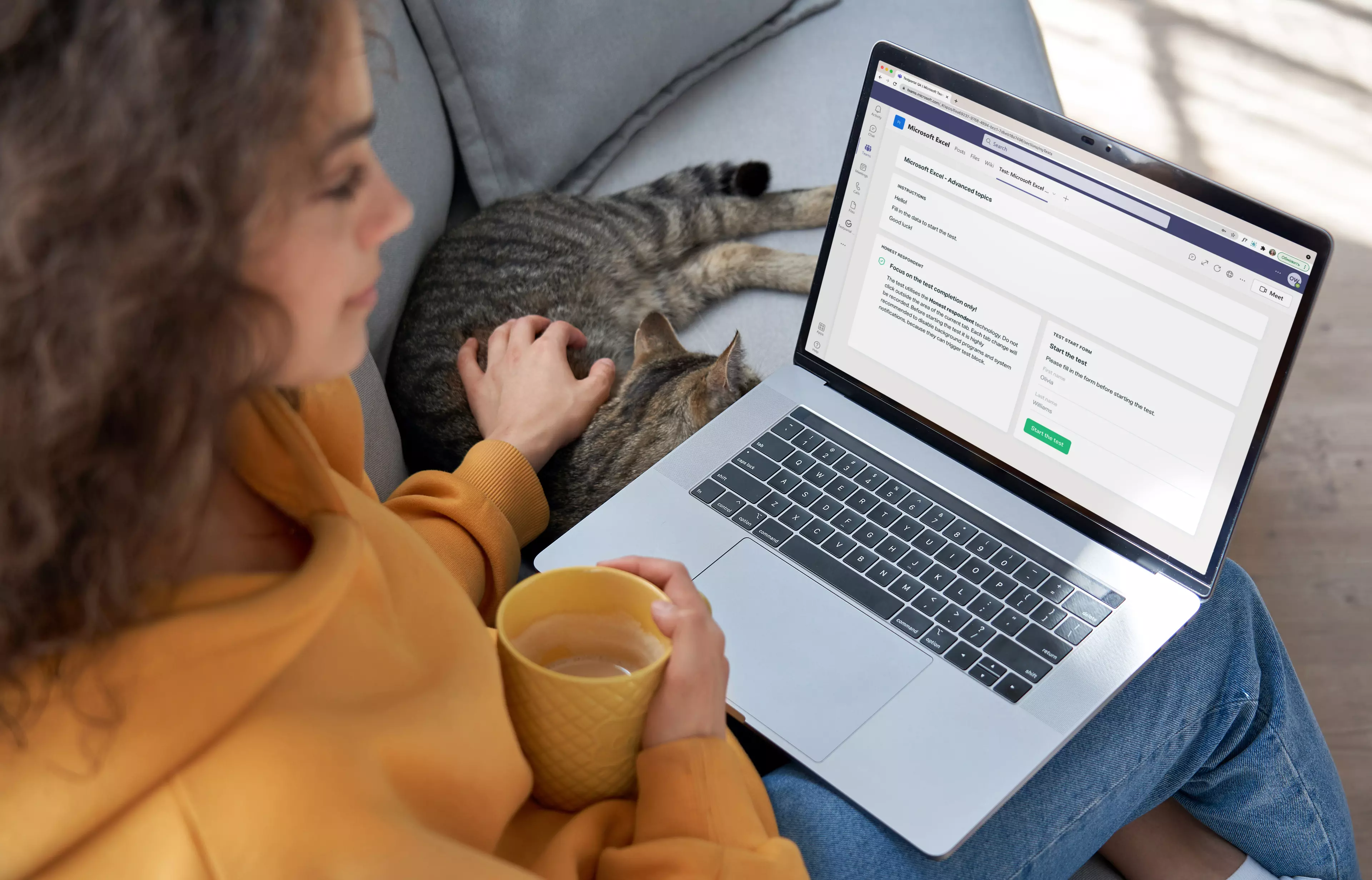  Woman with a notebook on her laps, holding a cup and petting a cat.