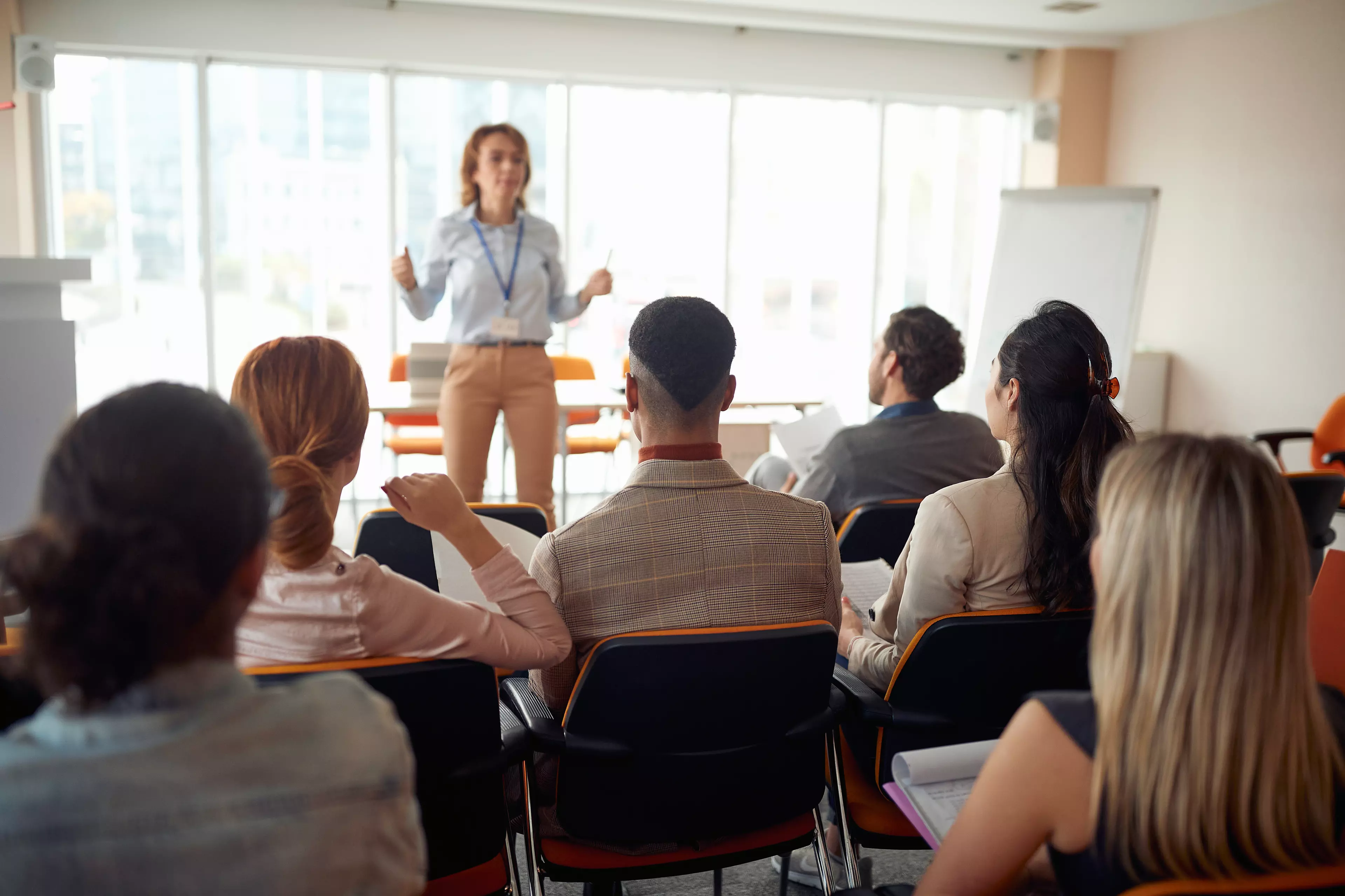 A team of employees sitting in front of a woman trainer.