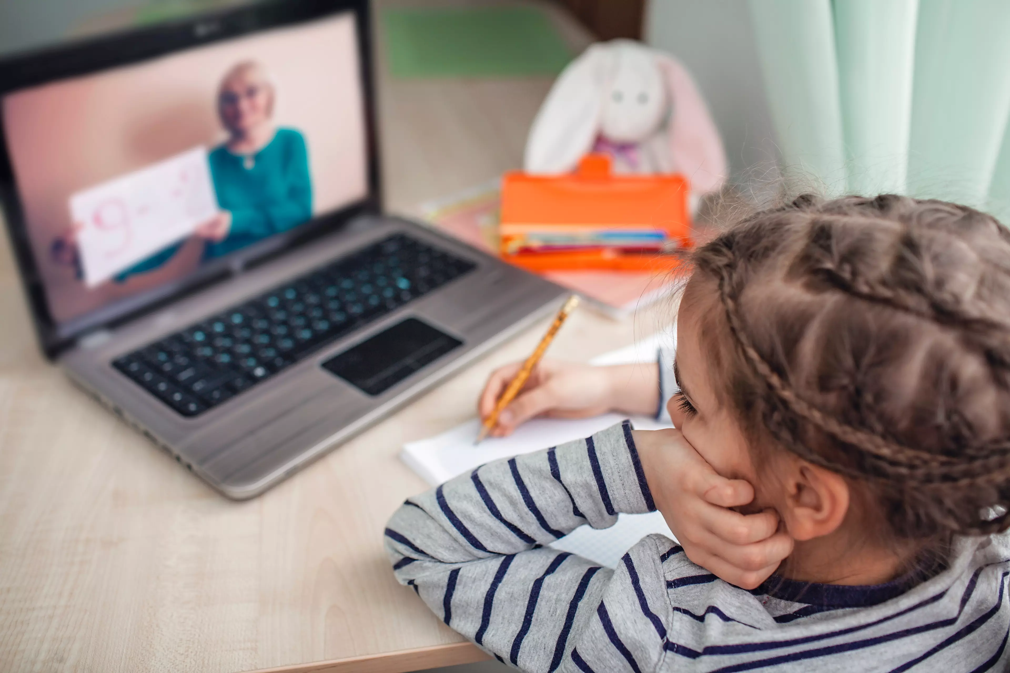 Young girl during online lesson at home, taking notes.