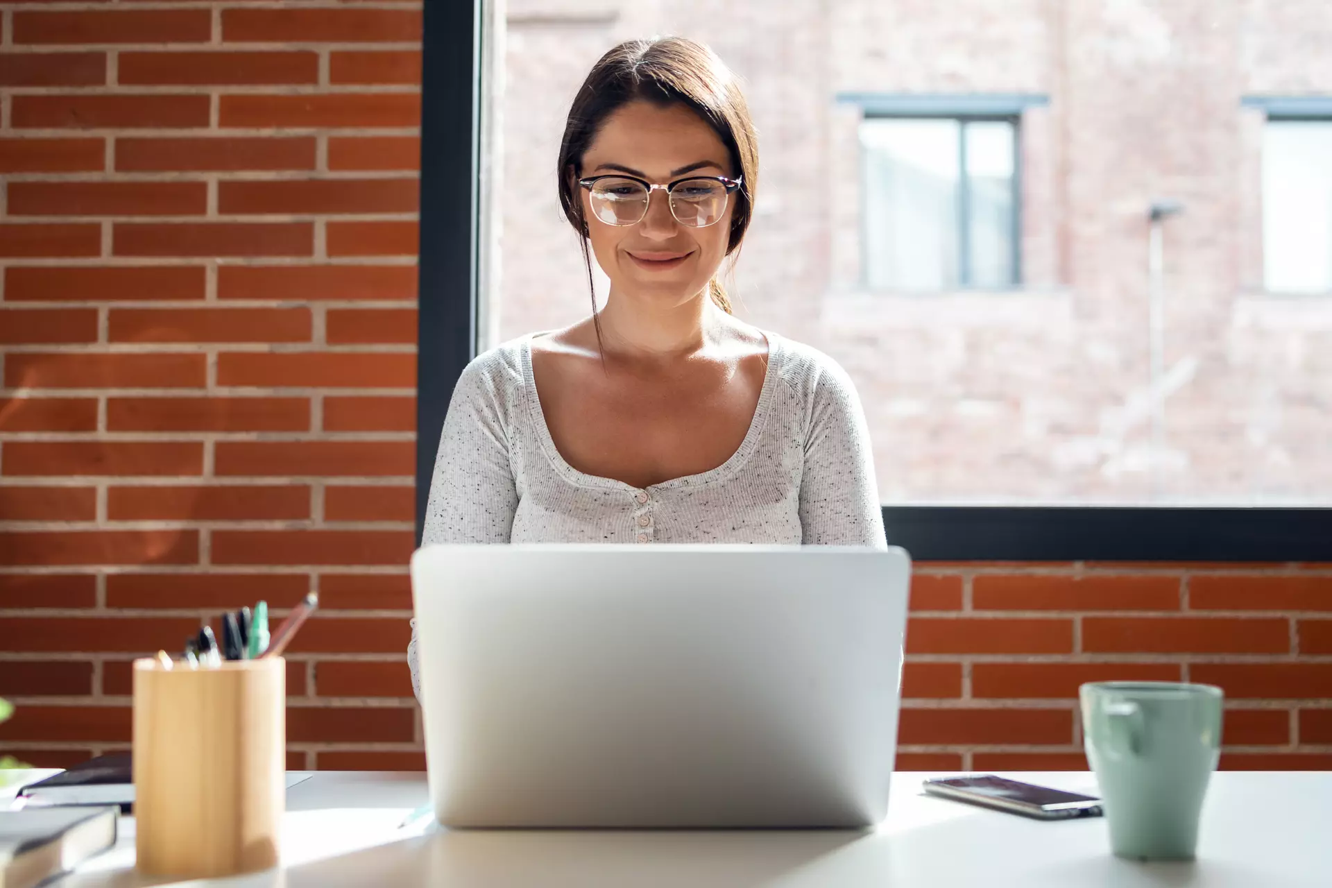 Young, smiling woman sitting in front of a laptop.