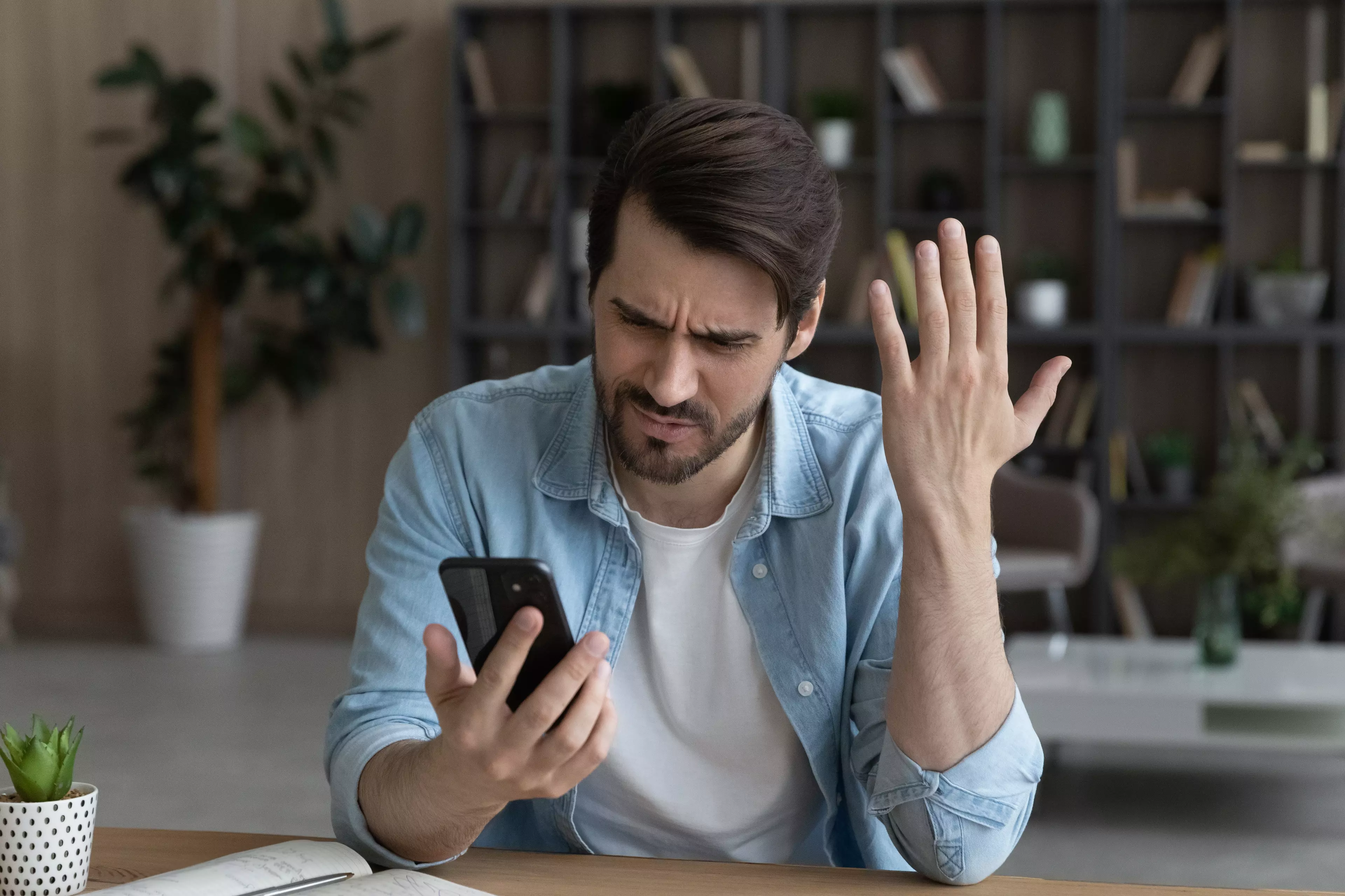 An irritated young man looking at his smartphone.