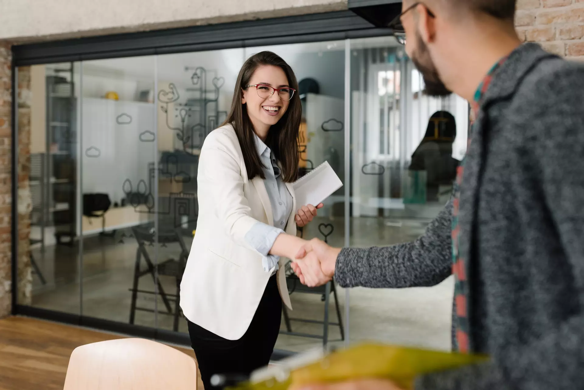 A man and a woman shaking hands in an office.