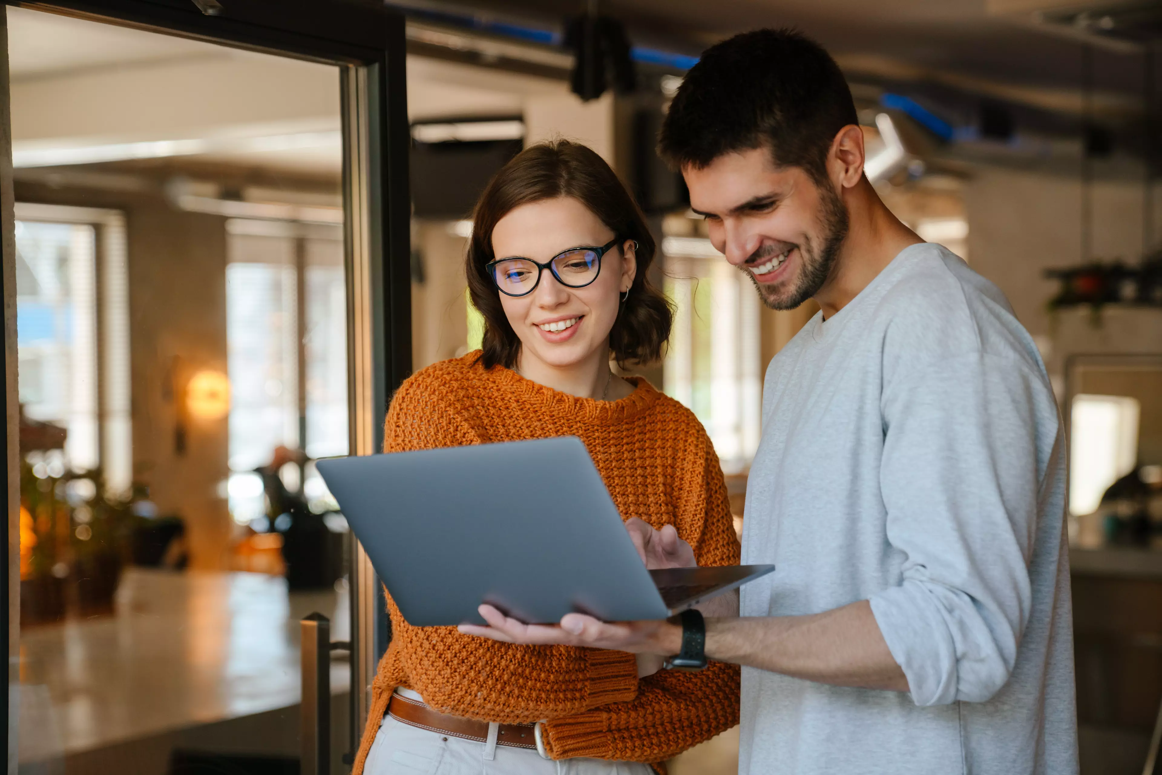 Smiling woman and man looking at a laptop in their office.