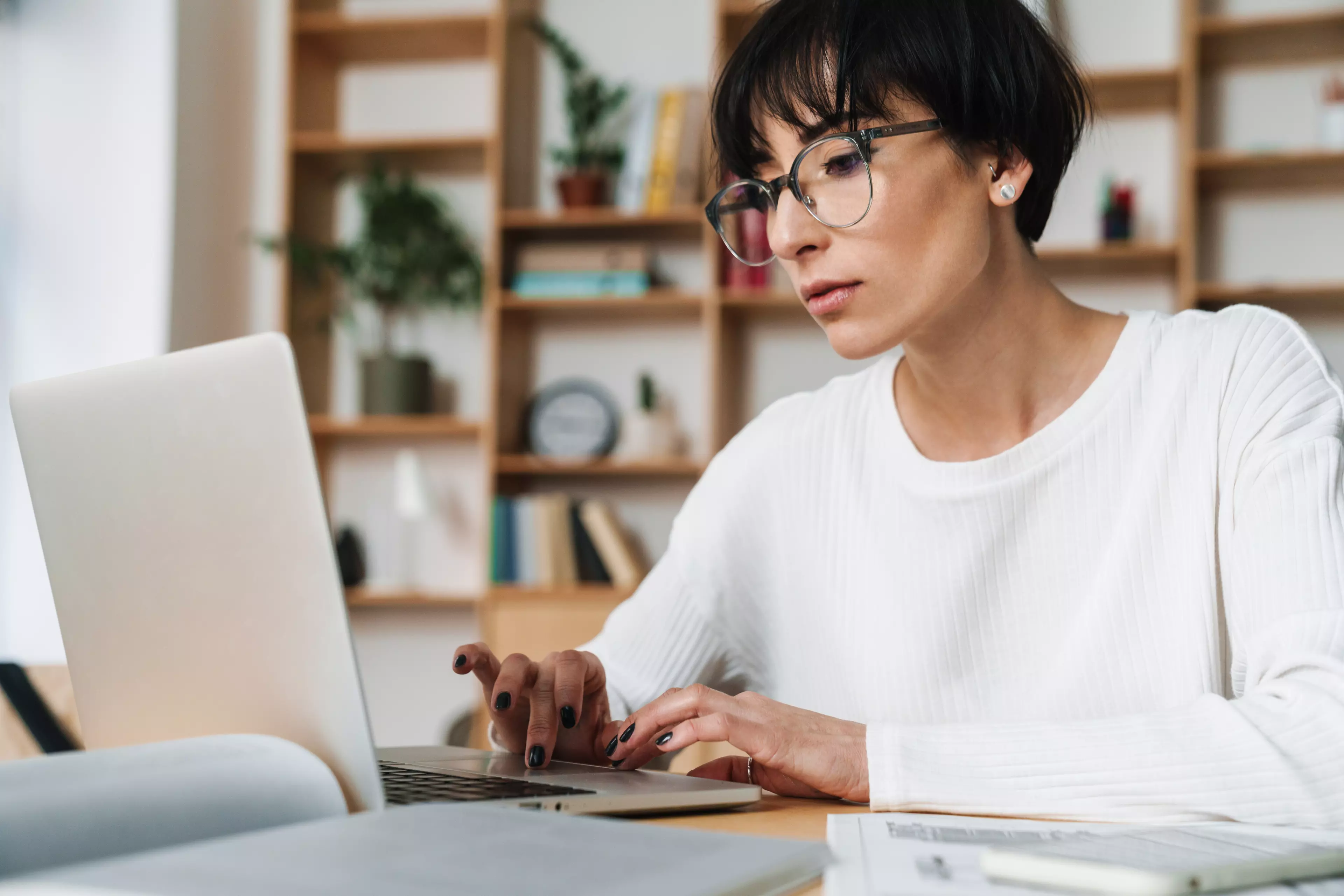  Woman sitting at a desk, typing on a laptop.