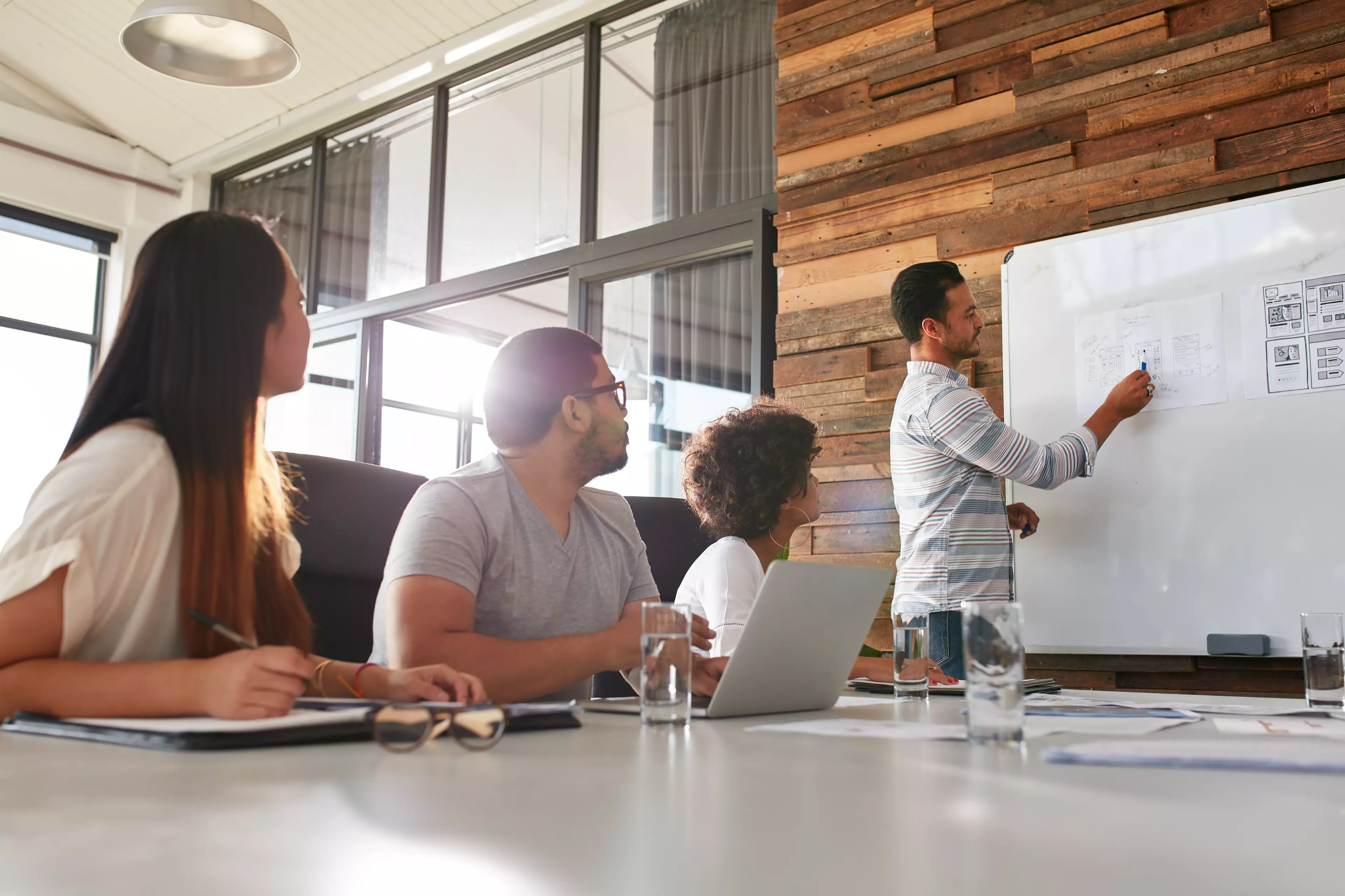  A man showing his team diagrams on a whiteboard during an office meeting 