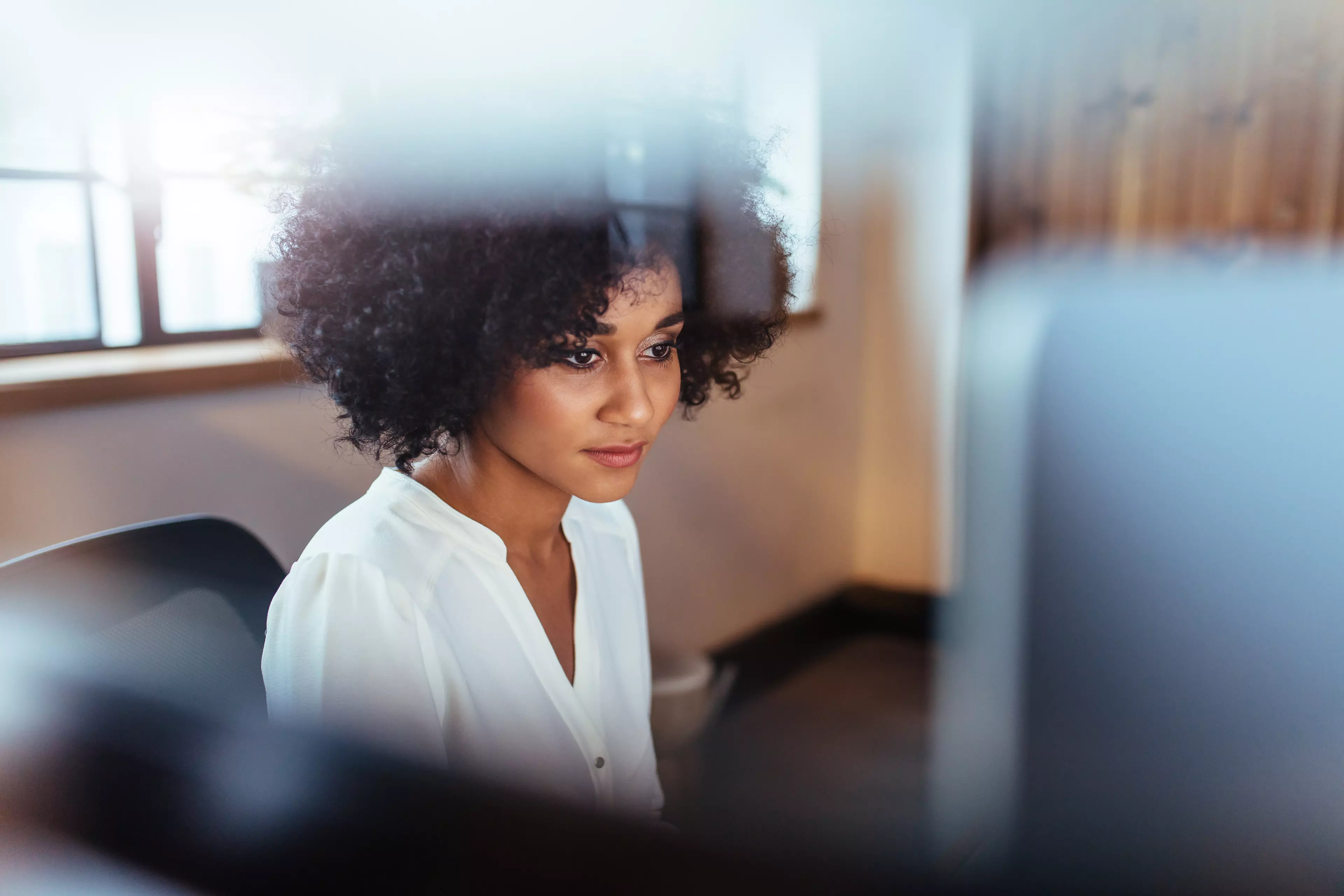 Young dark haired woman sitting in front of a desktop computer.